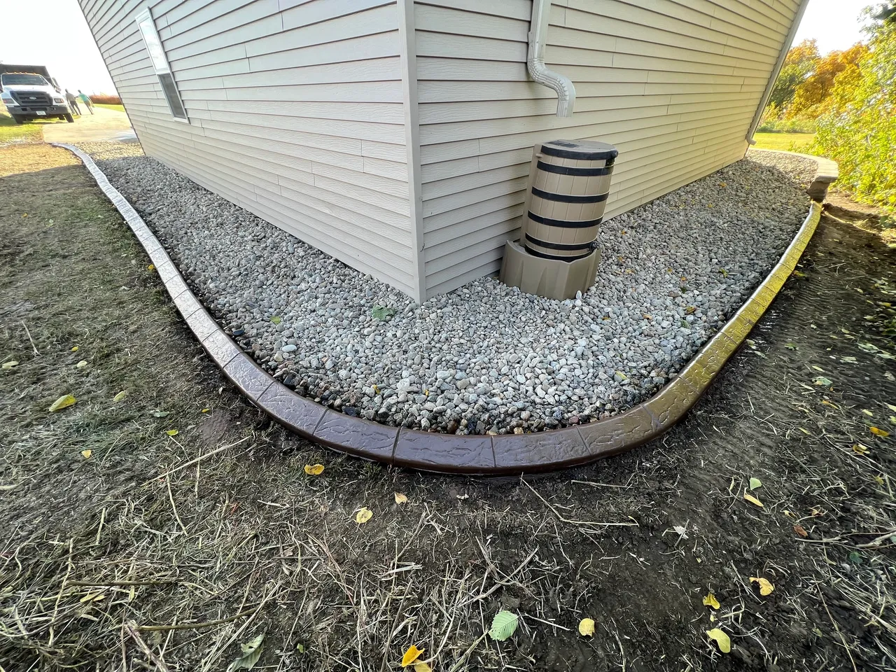 A corner of a house with gravel and concrete.