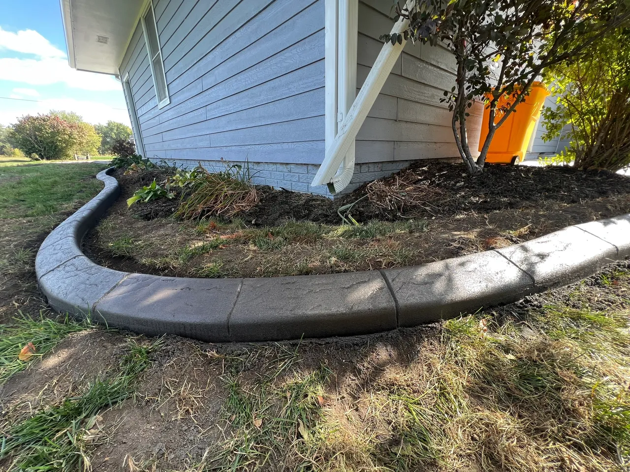 A concrete curb is laying in the grass.