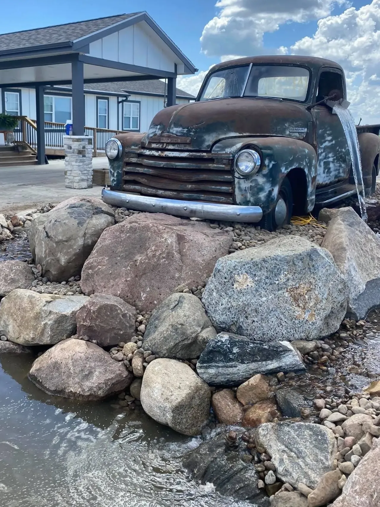 A truck is parked on some rocks near water.