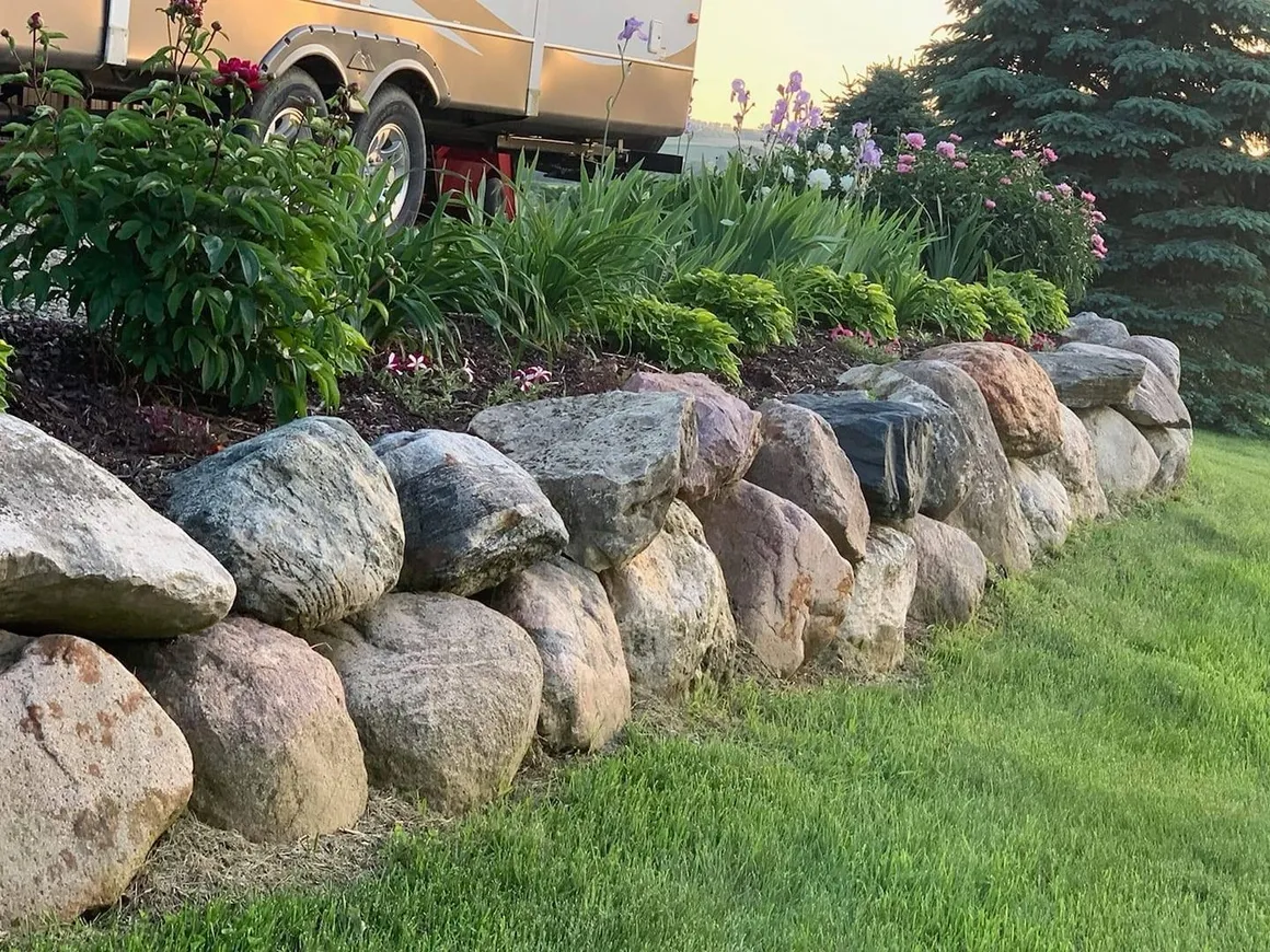 A large rock wall in the middle of a yard.