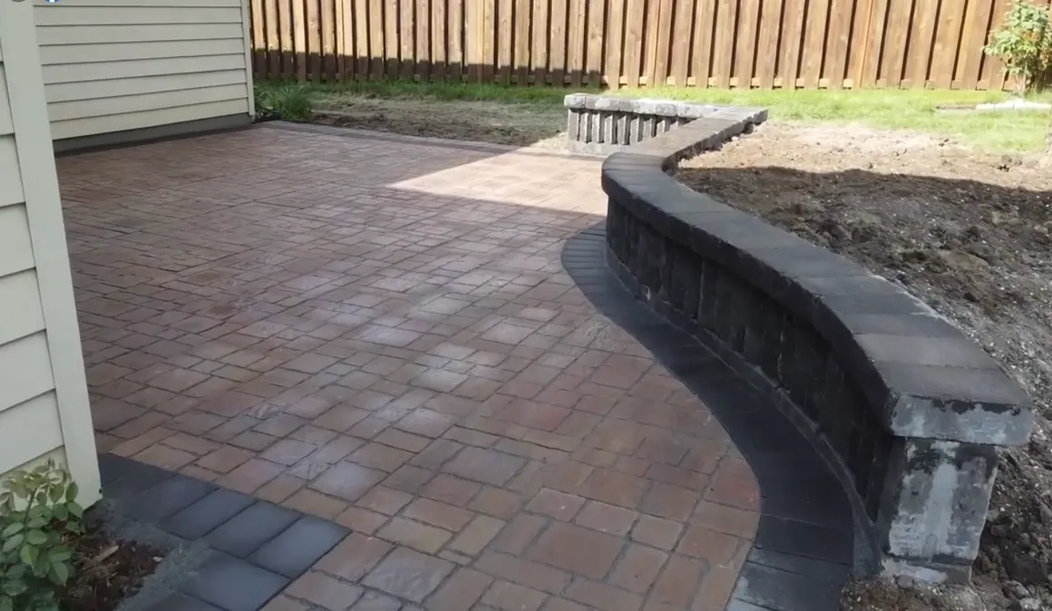 A brick patio with a bench and wall.