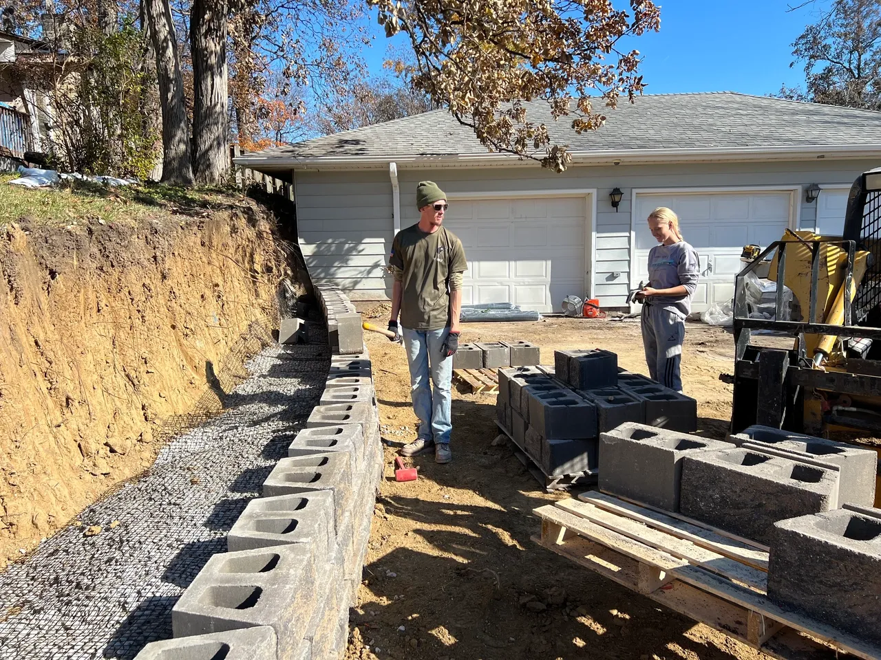 Two men standing next to a wall of concrete.