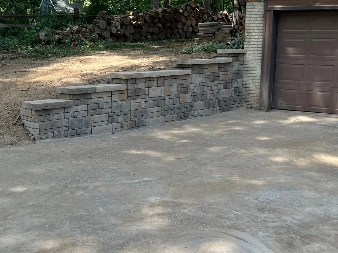 A driveway with a stone wall and garage door.