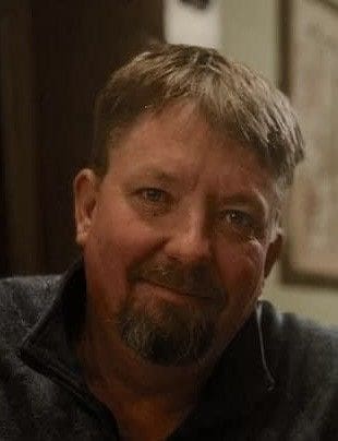 A man with a beard and mustache wearing a black shirt.