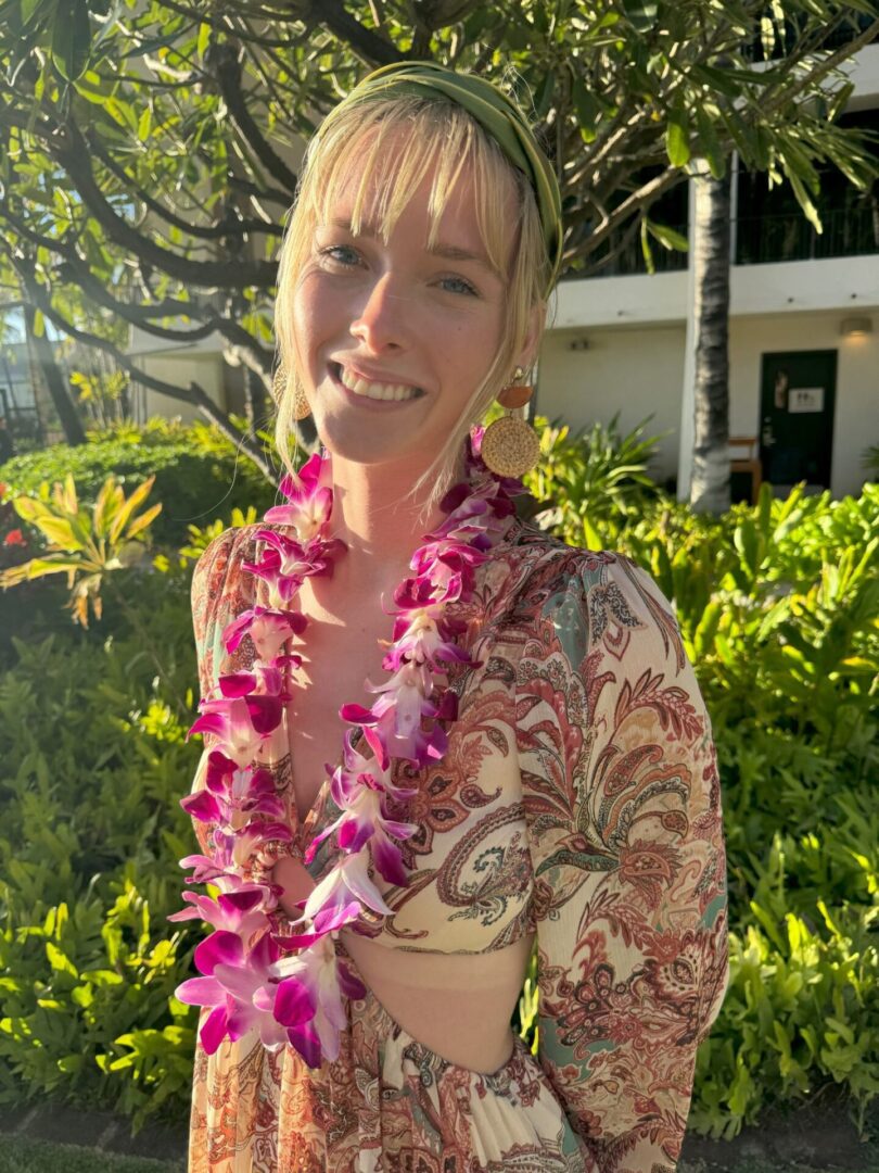 A woman wearing pink flowers in her hair and smiling.