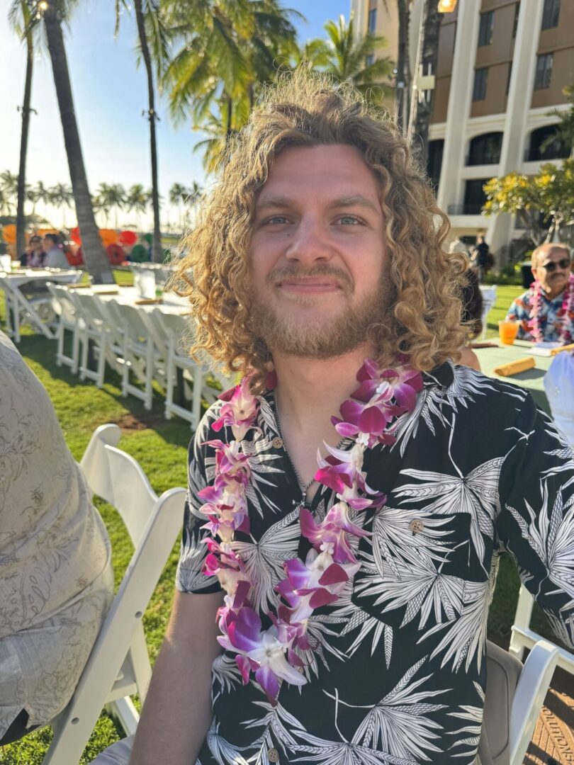 A man with long hair and a lei in his mouth.